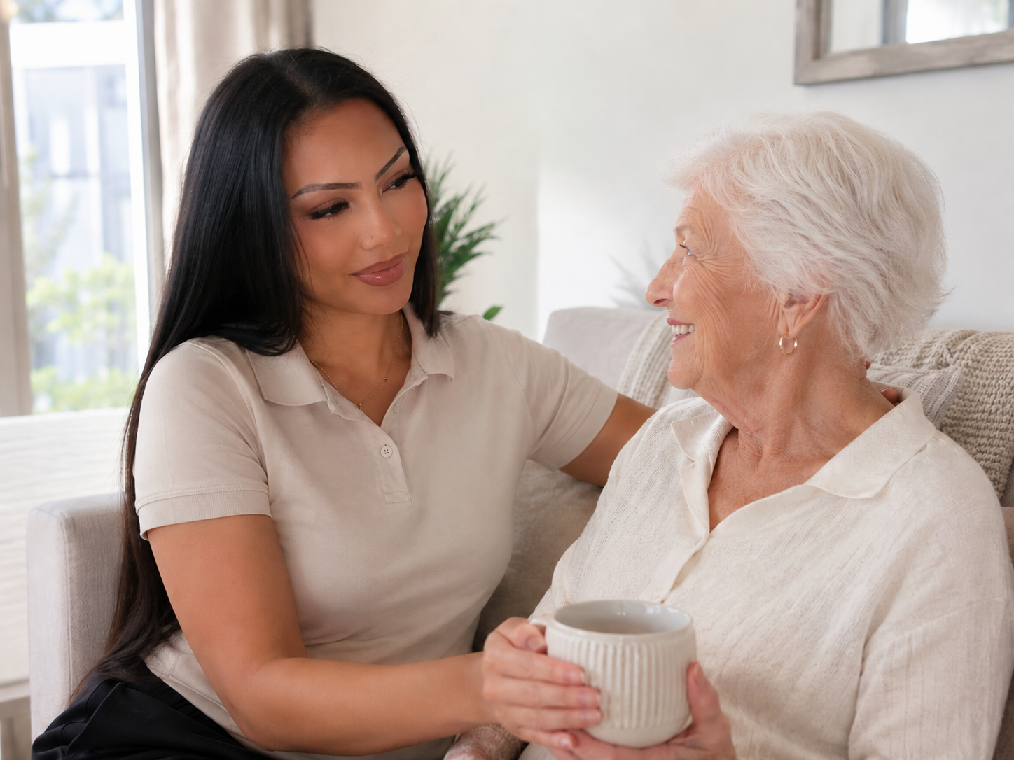 A Jicare nurse holding the hands of an elderly woman in her home, sharing a warm moment